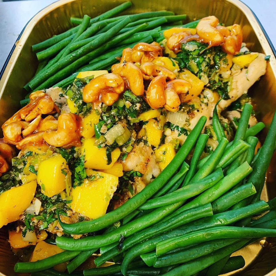 Chicken with mango, cashews, and green beans in a golden container from Hello Good Pie.